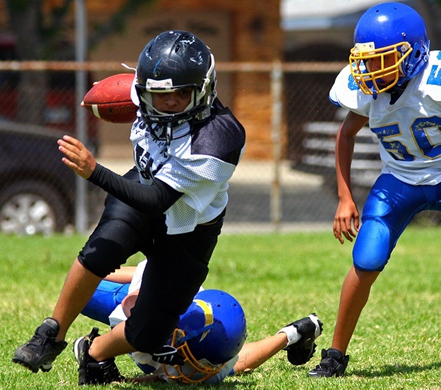 Teens playing football with athletic mouthguard in place