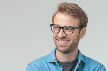 Man with glasses and blue button up shirt smiling